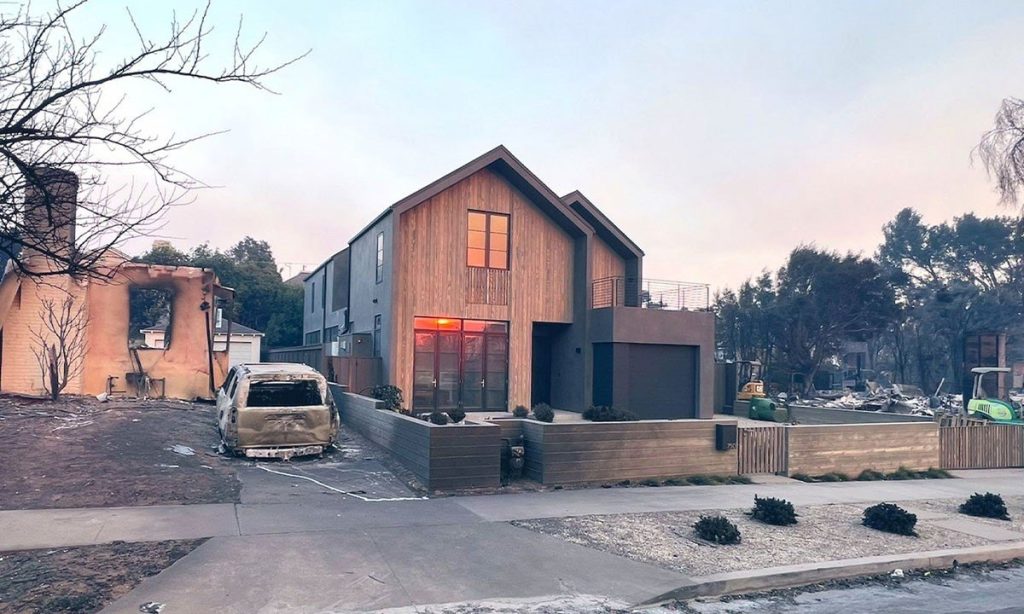 The "miracle" timber-clad Passive House on Iliff Street standing intact after the 2025 Los Angeles wildfires, surrounded by neighboring homes destroyed by fire.