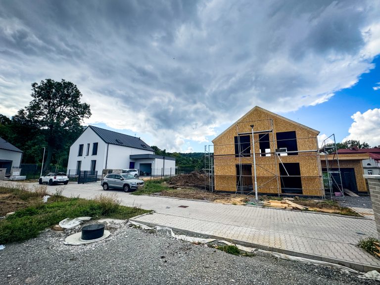 Modern mass timber house under construction with engineered wood panels and scaffolding in a residential neighborhood.
